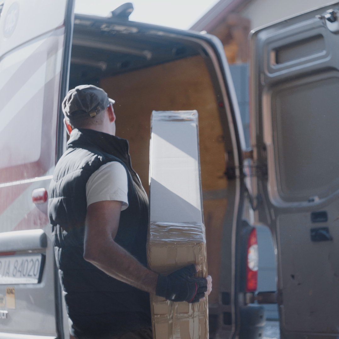 Pracownik pakujący paczkę do samochodu dostawczego